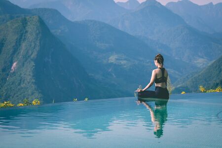Beautiful Attractive Asian woman practice yoga Lotus pose on the pool above the Mountain peak in the morning in front of beautiful nature views in SAPA vietnam,Feel so comfortable and relax in holidayの写真素材
