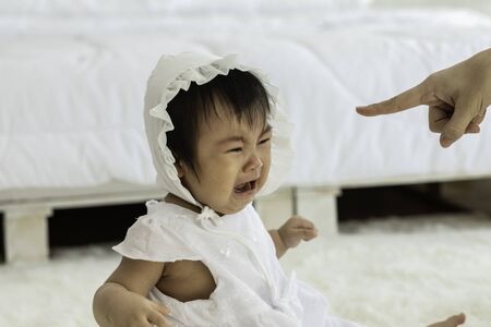 Mother scolding baby crying in bedroomの写真素材