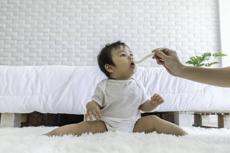 Mother feeding her Adorable baby at cozy home