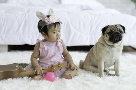 Cute Sweet Adorable Asian Baby wearing white dress Sitting on white bed smiling and playing with happiness emotional in cozy bedroom,Healthy Baby Conceptの写真素材