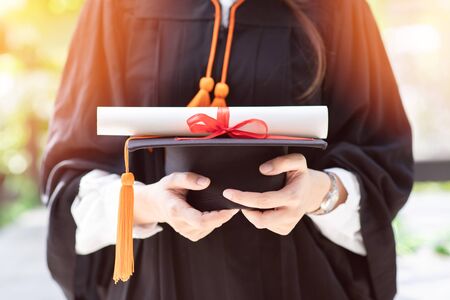 Close up graduation woman in gown holding graduation cap and certificated so proud and happiness for finish graduate,Education Success Concept の写真素材