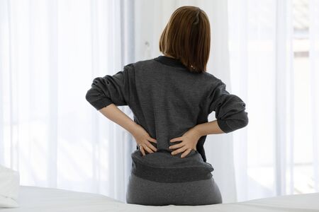 woman have a back pain sitting on bed after wake up in bedroom,Healthcare Concept
