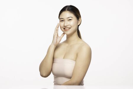 Attractive Charming Asian young woman smile with white teeth and touching soft cheek feeling so happy and cheerful with healthy Clean and Fresh Skin,isolated on white,Beauty Cosmetology Conceptの写真素材