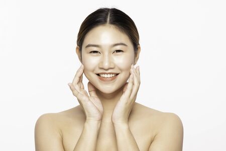 Beautiful Attractive Charming Asian young woman smile with white teeth and touching soft cheek feeling so happy and cheerful with healthy skin,isolated on white background,Beauty Cosmetology Conceptの写真素材