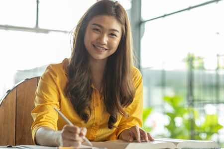 Beautiful Attractive Asian woman reading book and holding pencil thinking and writing data or business planning in paper for remember and learn,Writing Education Conceptの写真素材