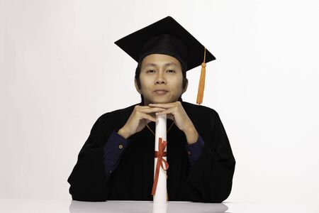 Asian Graduate man in cap and gown smile with certificated or diploma so proud and happiness in Graduation day,Isolated on white Background,Education Graduation Conceptの写真素材
