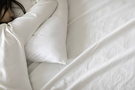 Asian woman wearing Pajamas sleep close her eyes lying face down on pillow sleep and sweet dream on...