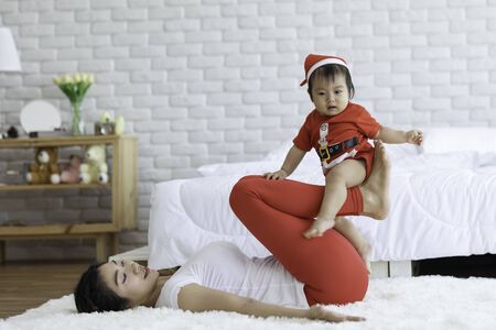 Attractive Mother Asian woman practice yoga with baby to meditation in bedroom after wake up in the morning Feeling so comfortable and relax,Yoga with Baby for Healthcare Conceptの写真素材
