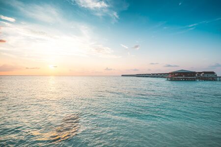 Beautiful villas over water on tropical island resort in Maldives with turquoise sea and...