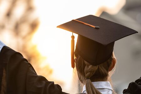 Back of view Graduate put hands up and celebrating with certificate in her hand and so proud and happiness in Commencement day,Congratulation of student in graduation day,Education Success Conceptの写真素材