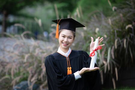 Attractive Asian Women Student Graduate in cap and gown celebrating with certificate in hand and so proud happiness in Commencement day,Congratulation of student in graduation day,Education Successの写真素材