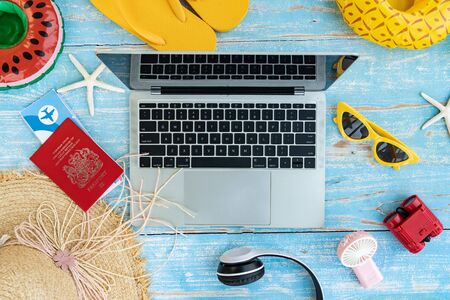 Summer Travel Beach accessories on blue wooden background,Top views of Computer laptop sunglasses starfish beach slippers and passport ready to travel vacation in summer,Flat Lay,Vacation Conceptの写真素材