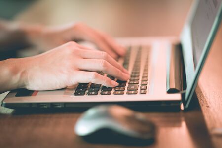 Close up hand of business woman working with laptop in coffee shop cafe,Warm tone,Selective focusの写真素材