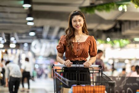 Beautiful Attractive Asian woman smile with shopping cart in supermarket feeling so happiness and enjoy,Shopping Conceptの写真素材