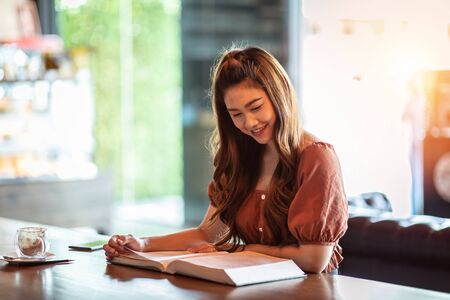 Beautiful Attractive Asian woman reading book for learn and education smile and positive thinking feeling so happiness and comfortable,Education Conceptの写真素材