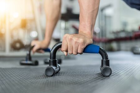 Attractive Handsome Asian young men workout with push up bar in gym focus on muscle feeling so strong and powerful,Bodybuilder conceptの写真素材