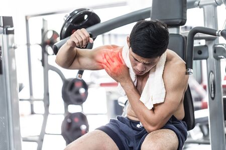 Asian man have injury muscle joint between shoulder and arm pain after workout in gym,Healthcare conceptの写真素材
