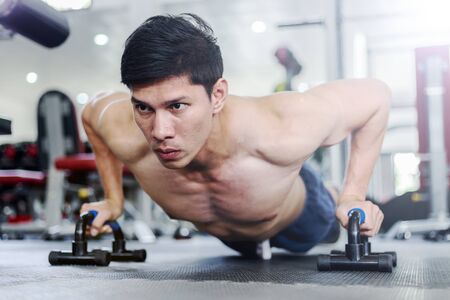 Attractive Handsome Asian young men workout with push up bar in gym focus on muscle feeling so strong and powerful,Bodybuilder conceptの写真素材