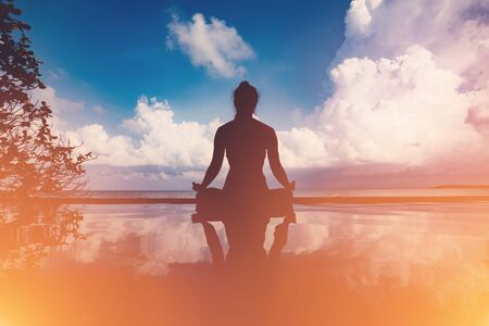 silhouette Athletic woman practice yoga lotus pose to meditation summer vacation on pier with sunset sea beach,Travel in tropical beach Thailand,vacations and relaxation Conceptの写真素材