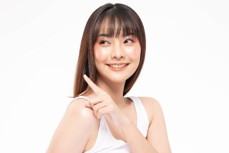 Beautiful Attractive Asian young women smile and pointing to copy space for display Cosmetics product feeling happiness with Healthy Clean and Fresh Skin,Isolated on white background,Beauty Conceptの写真素材