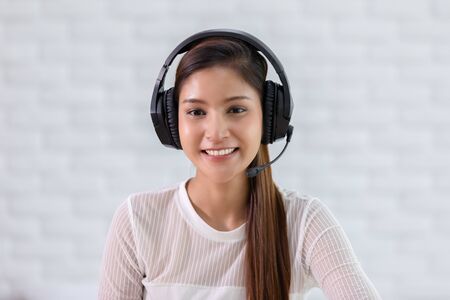 Camera view of Happy young asian business woman wears headset talk to online video conference call with her business team during quarantine covid-19 self isolation at home,VDO Call Conference Conceptの写真素材