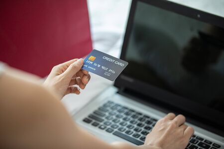 Close up Asian young woman using Credit card computer laptop for shopping online relax in bedroom in holiday,Lifestyle in bedroom Conceptの写真素材