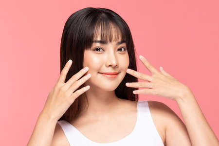Beautiful Asian woman touching soft cheek smile with clean and fresh skin Happiness and cheerful with positive emotional,isolated on pink background,Beauty Cosmetics and spa Treatment Conceptの写真素材