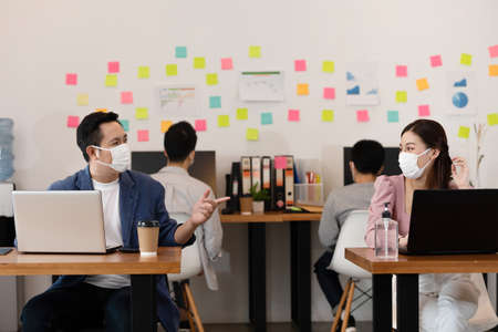 Business man and woman wearing face mask meeting and working together for discussion and brainstroming to get ideas or marketing solution with social distance due virus pandemicの写真素材