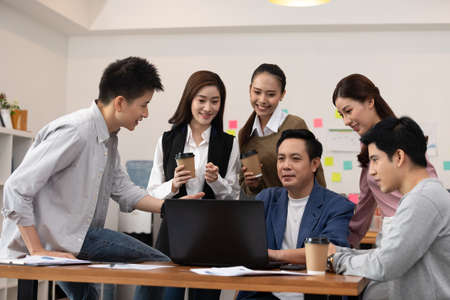 Group of young Startup coworkers working together looking at laptop and celebrating with success they job at office,Business Startup Diversity Brainstorming Conceptの写真素材