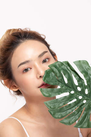 Young Beautiful Asian woman smile with clean and fresh skin with green leaf cover on face,isolated on white background,Beauty Cosmetics and spa Treatment Conceptの写真素材