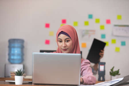 Asian business Muslim or islam women in casual working with laptop and smile looking at camera at modern office or Co-Working Space,Business Startup Conceptの写真素材