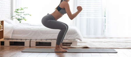 Banner Athletic Healthy Asian indian woman in sportswear workout squat excercise at home in...