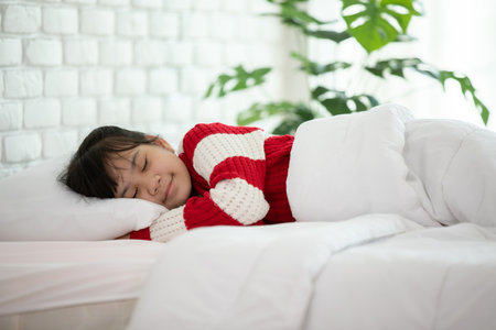 Asian girl kid wearing Pajamas close her eyes smile sleep and sweet dream on bed in bedroom in the morning feeling so relax and comfortable,Healthcare and Sleep Conceptの写真素材