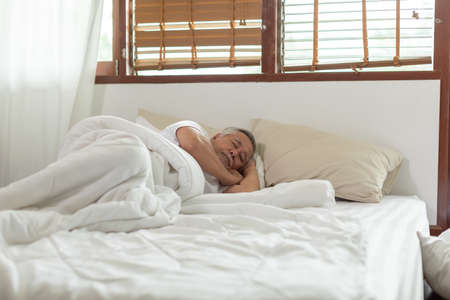 Asian Elderly man close eyes smile sleep and sweet dream on bed in bedroom in the morning feeling so relax and comfortable,Healthcare and Sleep Conceptの写真素材