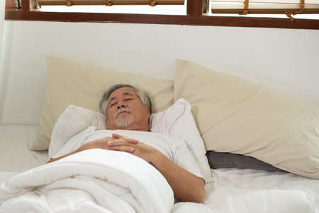 Asian Elderly man close eyes smile sleep and sweet dream on bed in bedroom in the morning feeling so relax and comfortable,Healthcare and Sleep Conceptの写真素材