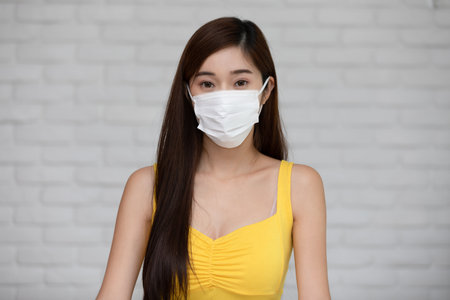 Asian young woman smile and wearing medical surgical face mask for protection from virus and dust in the air due virus pandemic happiness and confidentの写真素材