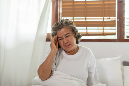 Asian Elderly senior woman sudden headache and migraine so pain and illness on bed alone at home,Elderly Care Conceptの写真素材
