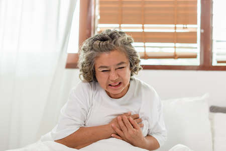 Emergency of Asian Elderly senior woman with white hairs sudden heart attack chest pain and illness on bed alone at home,Elderly Care Conceptの写真素材