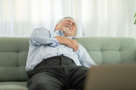 Emergency of Asian Elderly senior man sudden heart attack so pain on chest and illness with diabetes symptoms on sofa due working alone and need Urgently help at home,Elderly care conceptの写真素材