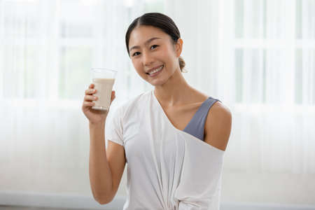 Healthy Young Asian woman Drinking milk with calcium for strong bone at home,Smiling indian woman...