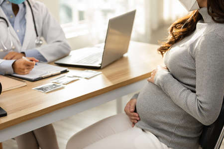 Professional Asian doctor woman consulting pregnant patient,Smart Doctor wearing white coat with stethoscope talking to patient at hospital,Doctor and Pregnancy Patient Conceptの写真素材