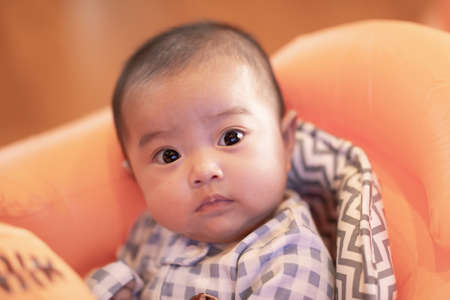 Adorable Asian baby girl lying on bed looking at camera.Cute little baby smiling and happiness relaxing in bed.Portrait of asian baby newborn in bedroom,Soft focusの写真素材
