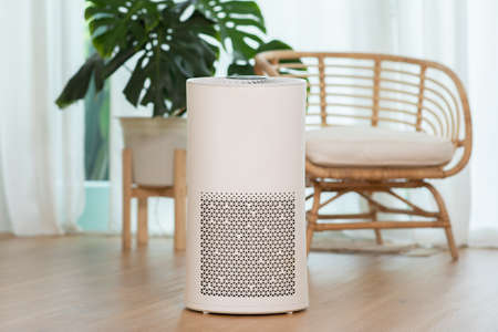 Air purifier in cozy white living room for filter and cleaning removing dust PM2.5 HEPA and virus in home,for fresh air and healthy Wellness life,Air Pollution Conceptの写真素材