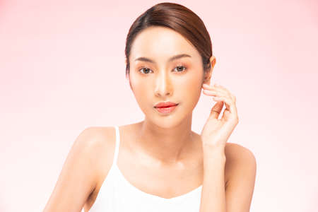 Young Beautiful Asian woman smile touching soft cheek with clean and fresh skin Happiness and cheerful with positive emotional,isolated on pink background,Beauty Cosmetics and spa Treatment Conceptの写真素材