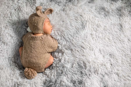 Back view happy newborn baby weaing cute rabbit costume lying sleep on grey carpet background comfortable with copy space.Cute Asian infant sleeping napping on baby bed.Newborn Baby Easter Day Conceptの写真素材