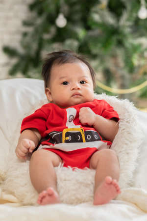 Cute Newborn baby wearing santa costume lying and moving hand and body waiting for celebrate merry...