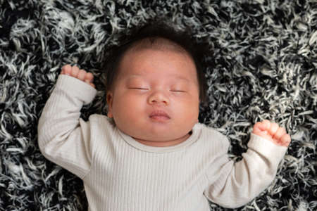 Top view happy newborn baby lying sleeps on a carpet comfortable and safety.Cute Asian newborn...