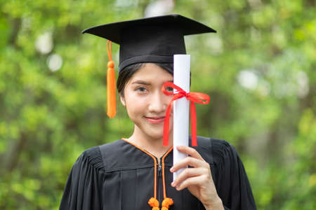 Attractive Asian Women Student Graduate in cap and gown celebrating with certificate in hand and so proud happiness in Commencement day,Congratulation of student in graduation day,Education Successの写真素材