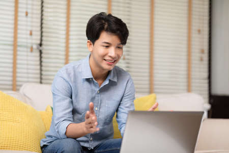 Entrepreneur handsome business asian man wear casual blue shirt working video call conference online with laptop,talking with customer or business team at home office.Small Business Startup Conceptの写真素材
