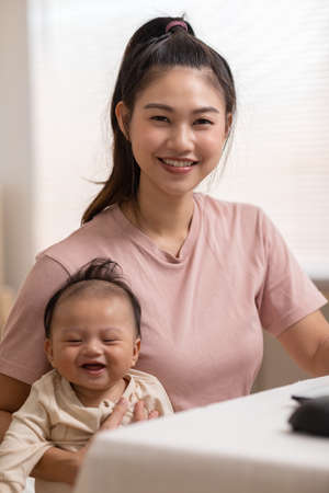 Adorable newborn baby smile and relax in mother arm safety and comfortable.Healthy Asian newborn infant baby laughing with happiness good moment.Mother holding infant baby.Newborn Baby conceptの写真素材
